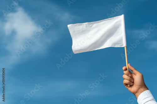 Hand raised with a white flag against a clear blue sky signaling peace or surrender photo