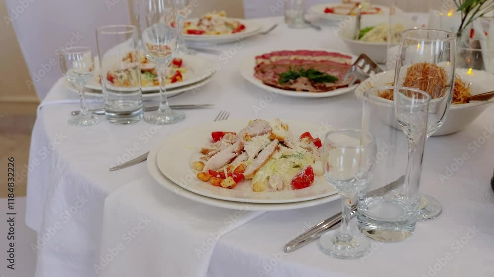 Caesar salad occupies a prominent place on a beautifully decorated table, surrounded by other dishes, empty glasses, and cutlery, suggesting a formal dining event Caesar salad occupies a prominent place on a beautifully decorated table, surrounded by other dishes, empty glasses, and cutlery, suggesting a formal dining event