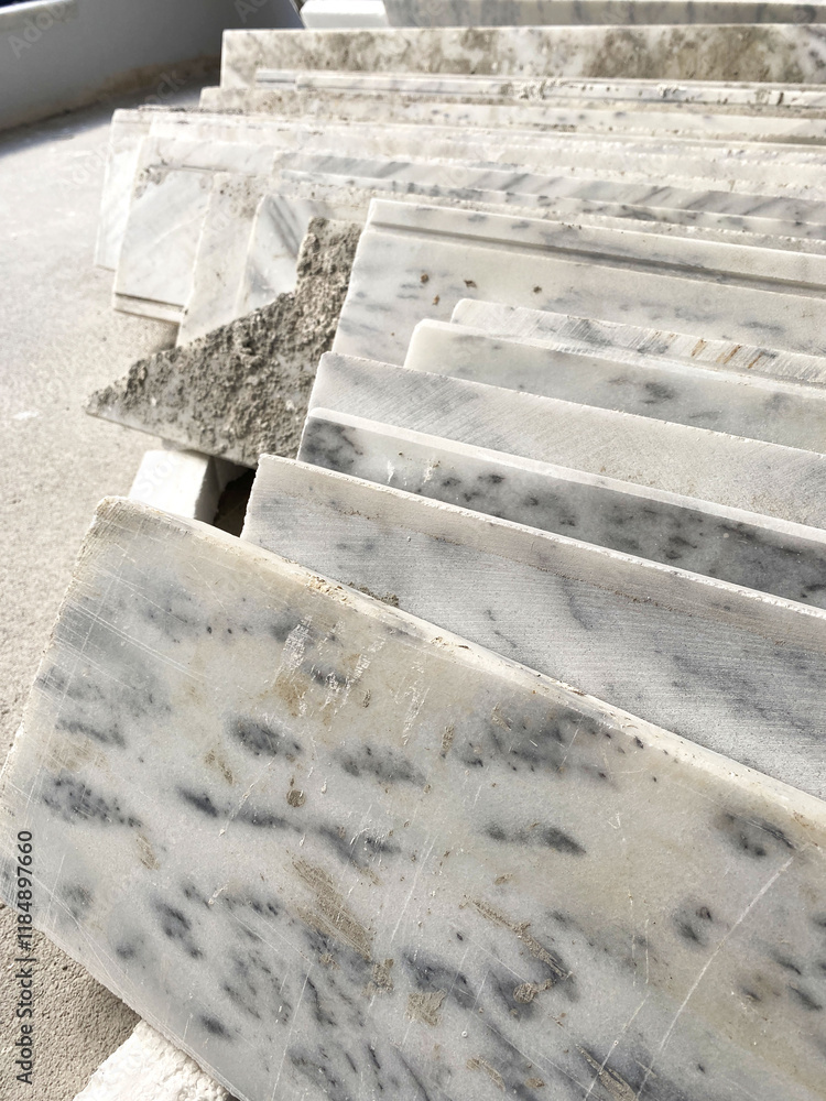 Stacked Marble Tiles with Rough Edges. A collection of marble tiles stacked in layers, featuring natural veining, rough edges, and construction debris in a bright outdoor setting. Stacked Marble Tiles with Rough Edges. A collection of marble tiles stacked in layers, featuring natural veining, rough edges, and construction debris in a bright outdoor setting.