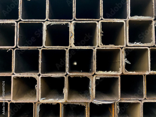 This closeup shows a neatly arranged stack of square metal pipes, highlighting their robust structure. Made from durable steel, these pipes are essential building materials