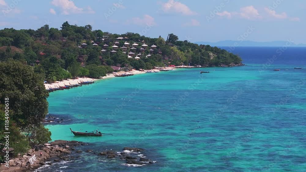 Aerial view of Phi Phi Island in Thailand with turquoise waters, scattered boats, lush green coastline, and distant islands under a clear sky. Aerial view of Phi Phi Island in Thailand with turquoise waters, scattered boats, lush green coastline, and distant islands under a clear sky.