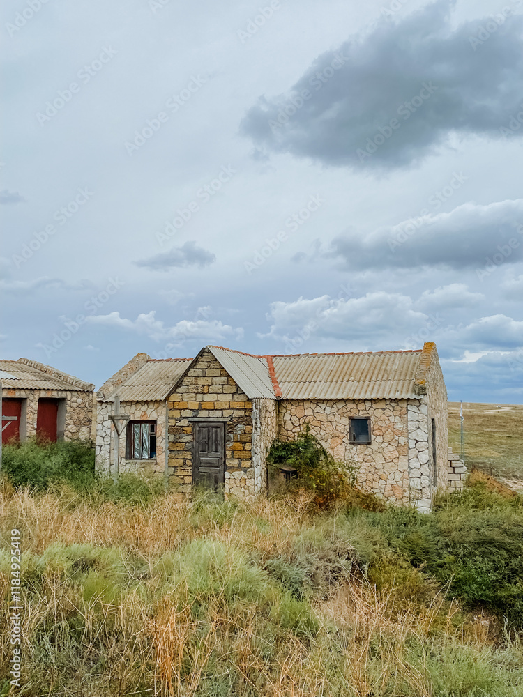 Obraz premium An old, sturdy stone house is comfortably sitting right in the middle of a vast open field, surrounded by natures beauty and tranquility, evoking a sense of peace and nostalgia