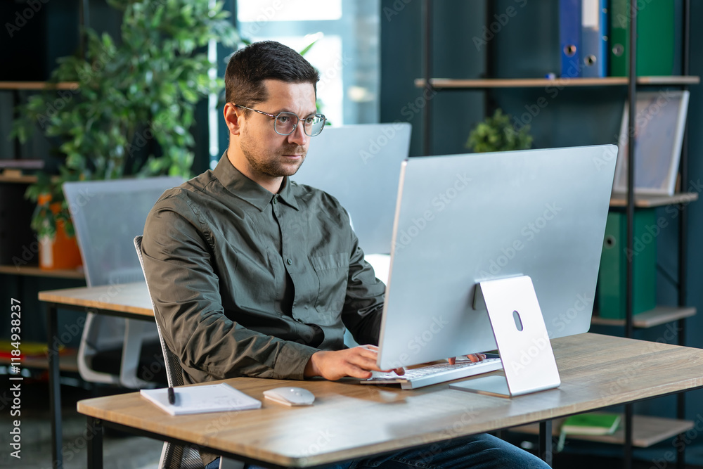 Side view portrait of modern IT developer using computer in office while working on VR games and software, copy space Side view portrait of modern IT developer using computer in office while working on VR games and software, copy space