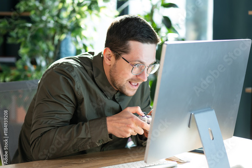 Funny confused office worker happy man employee gamers hold controller joystick playing video game on computer. Male gamer having fun free time at work. photo