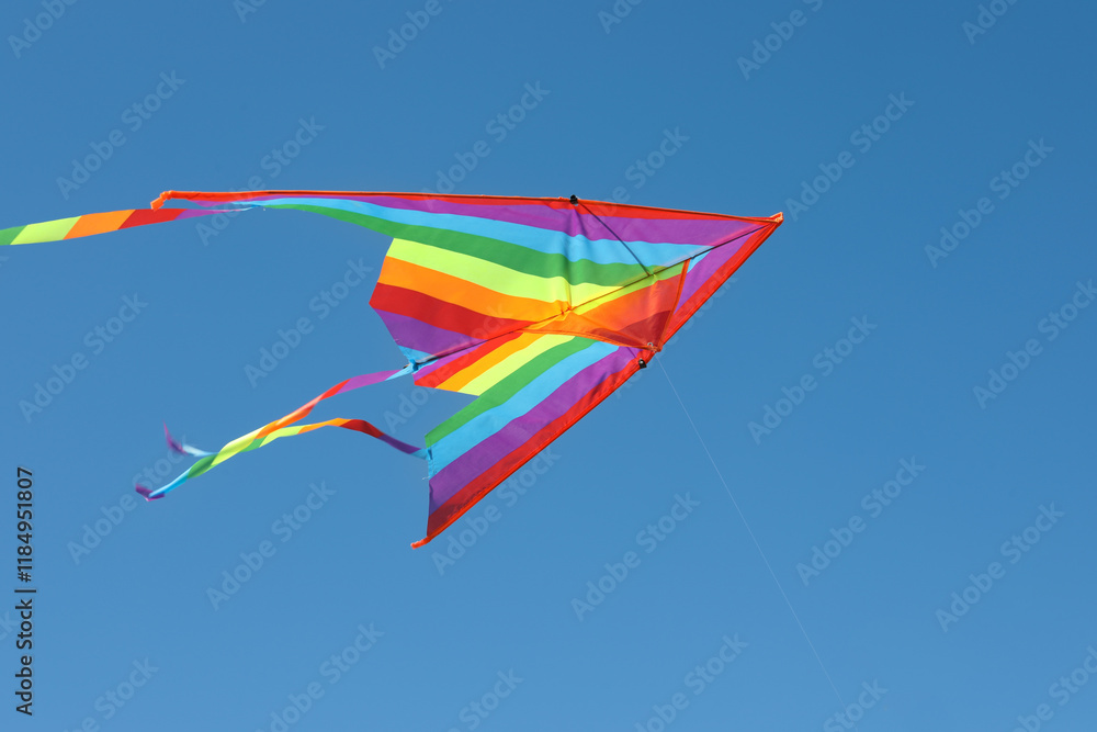 One colorful kite flying in blue sky One colorful kite flying in blue sky