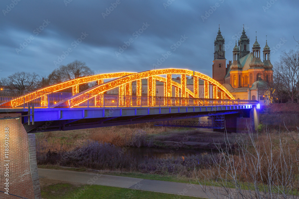Fototapeta premium Illuminated bridge to the cathedral on Tumski Island at sunrise, Poznan, Poland