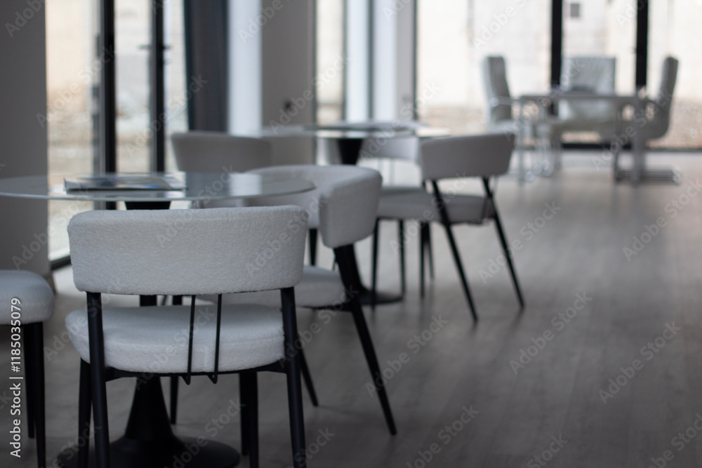 Horizontal photo. Empty light interior of cafe, cozy office room, canteen, coworking with white chair, round glass table without people. Concept of lunch, dinner, work, job, business. Desk. City day Horizontal photo. Empty light interior of cafe, cozy office room, canteen, coworking with white chair, round glass table without people. Concept of lunch, dinner, work, job, business. Desk. City day