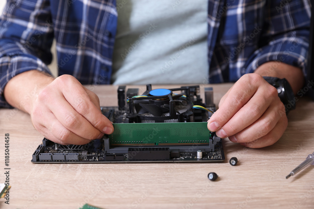 Man installing computer chip onto motherboard at wooden table, closeup Man installing computer chip onto motherboard at wooden table, closeup