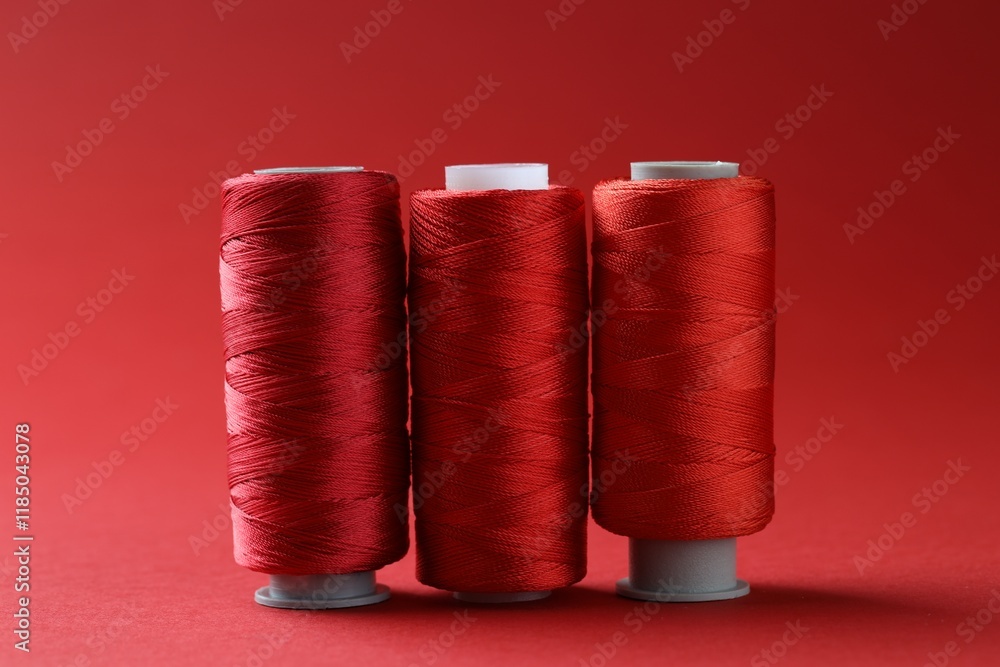 Spools of bright sewing threads on red background Spools of bright sewing threads on red background