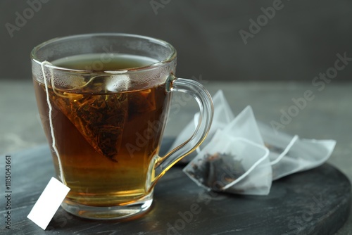 Tea bag in glass cup with hot drink on gray table, closeup photo