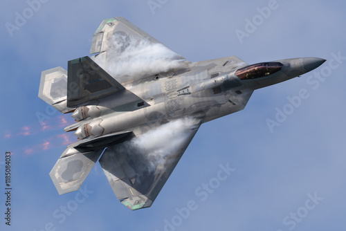 Close top view of a F-22 Raptor in beautiful light in a turn, with condensation clouds at the wing roots