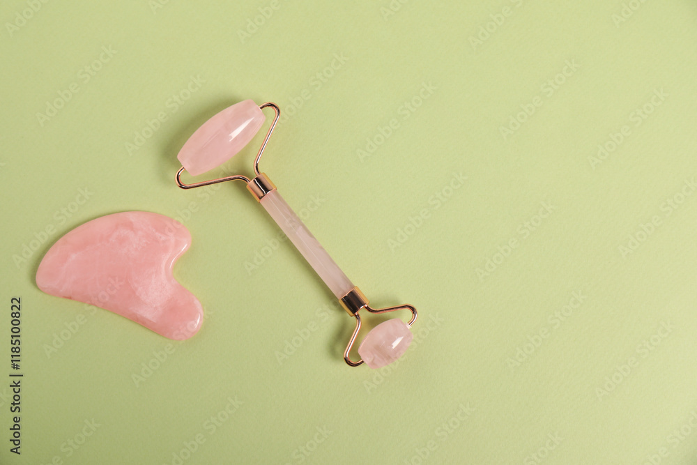 Face roller and gua sha tool on light green background, top view. Space for text Face roller and gua sha tool on light green background, top view. Space for text