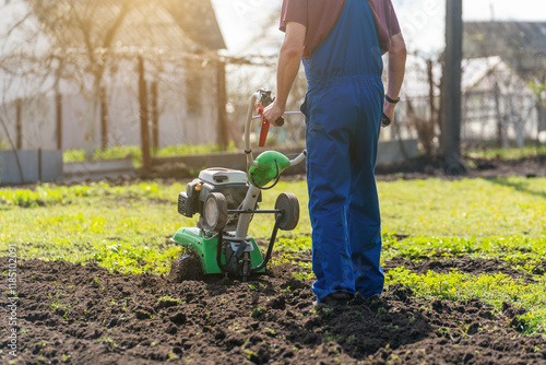 A man engaged in agriculture plows the soil with a cultivator for further planting of vegetables
