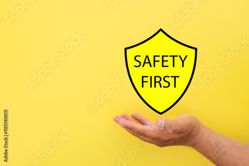 Hand holding security guard icon with safety first text over yellow background with copyspace.,Risk management and awareness,Attention,Danger concept. photo