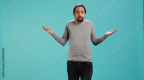 Man shrugging shoulders, unable to provide answer, having detached apathy facial expression. Apathetic person doing hand gesturing showing lack of knowledge, studio background, camera A