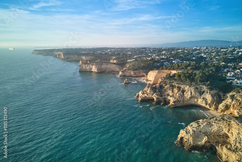 Stunning aerial view of the rocky shoreline extending into the distance in warm golden light. Algarve, Portugal