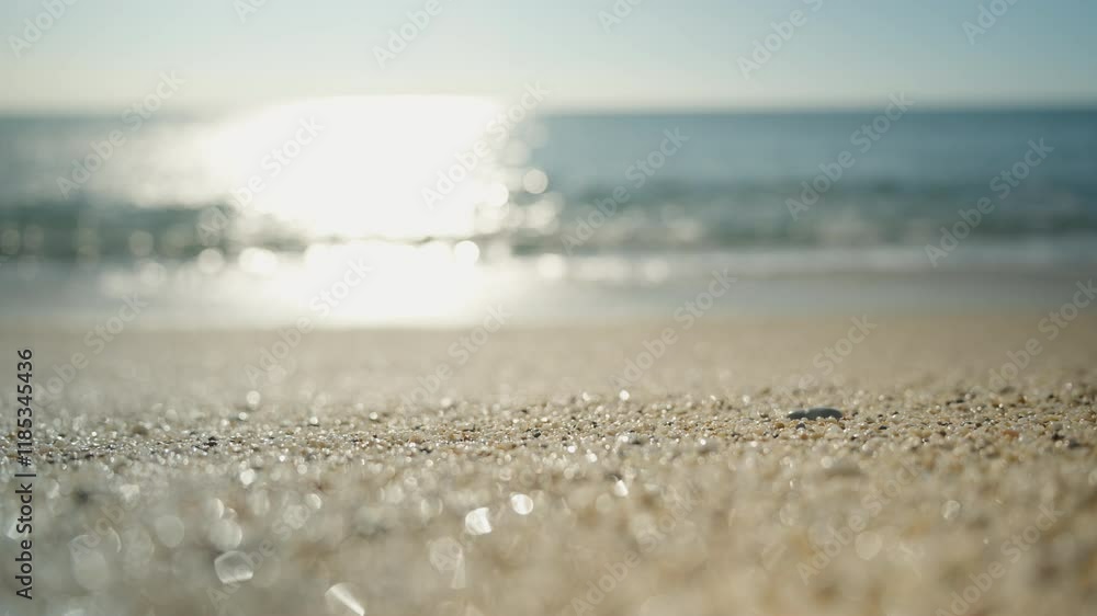 Glittering Beach Sand in Focus with a Sunlit Ocean and Horizon Blurred in the Background Creating a Minimalist and Peaceful Coastal Scene. Glittering Beach Sand in Focus with a Sunlit Ocean and Horizon Blurred in the Background Creating a Minimalist and Peaceful Coastal Scene.