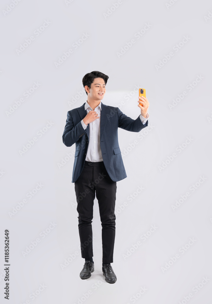 Full body image of a young Asian business man using phone and posing on a white background Full body image of a young Asian business man using phone and posing on a white background