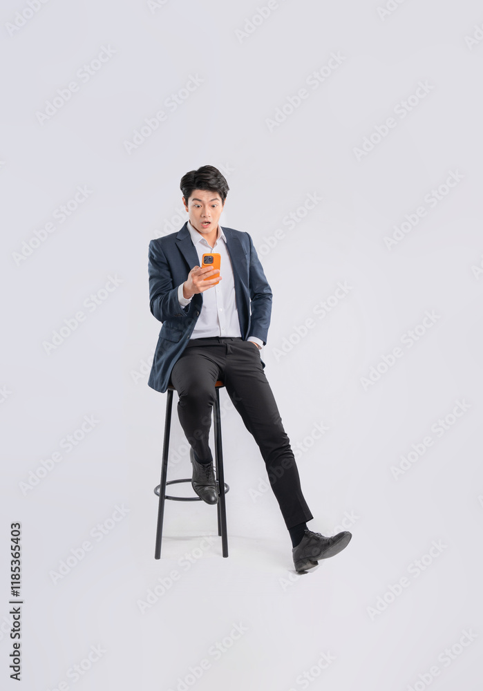 Full body image of young Asian business man using phone and sitting in chair on white background Full body image of young Asian business man using phone and sitting in chair on white background