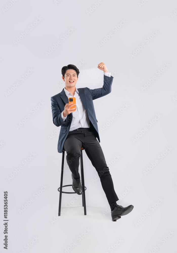 Full body image of young Asian business man using phone and sitting in chair on white background Full body image of young Asian business man using phone and sitting in chair on white background