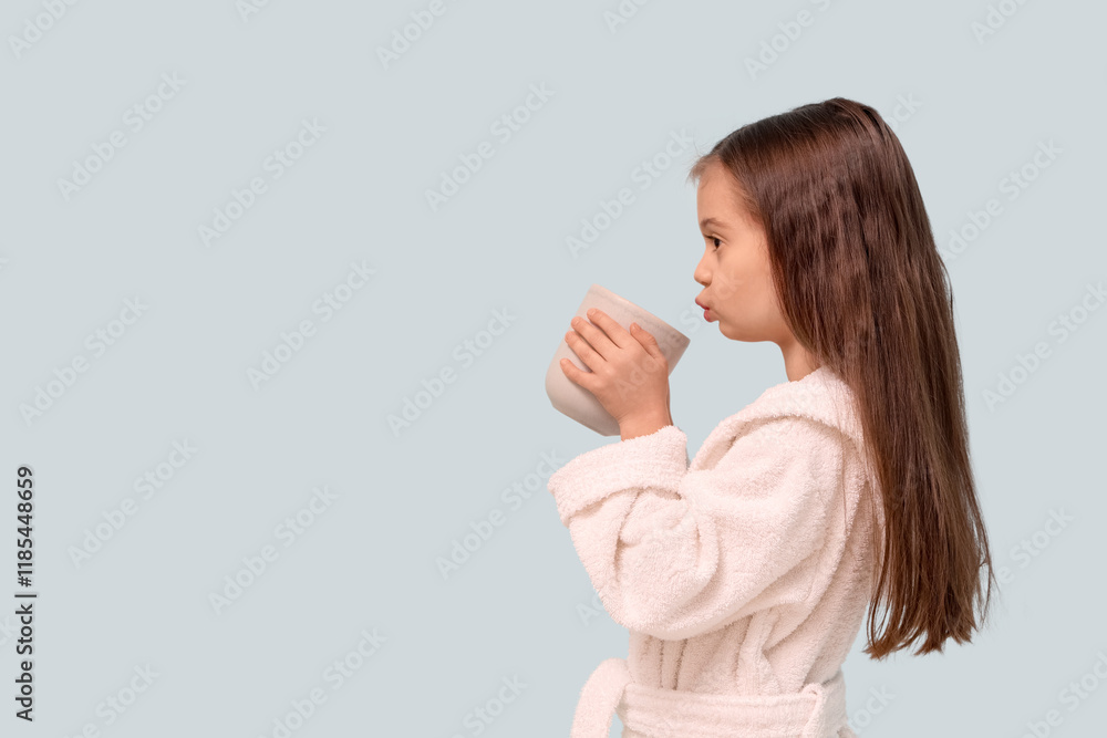 Cute little happy girl in bathrobe with cup of tea on blue background Cute little happy girl in bathrobe with cup of tea on blue background