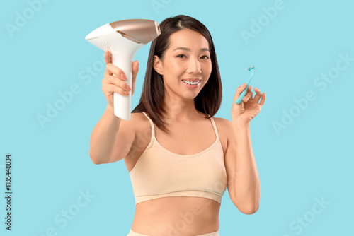 Young Asian woman with photoepilator and razor on blue background photo