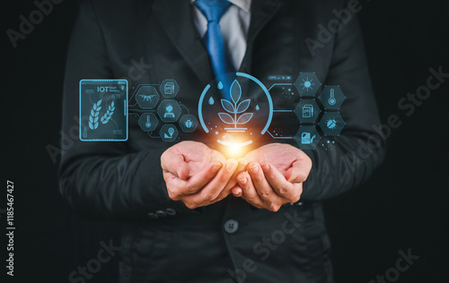 A businessman holds glowing symbols representing sustainability and technology, emphasizing innovation in a digital landscape.