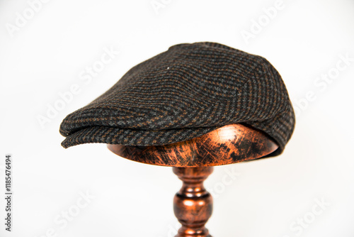 Detail of a newsboy hat made of wool fabric with a pattern mounted on a bronze mannequin head with a white background. classic newsboy hat photo concept on an elegant bronze mannequin
