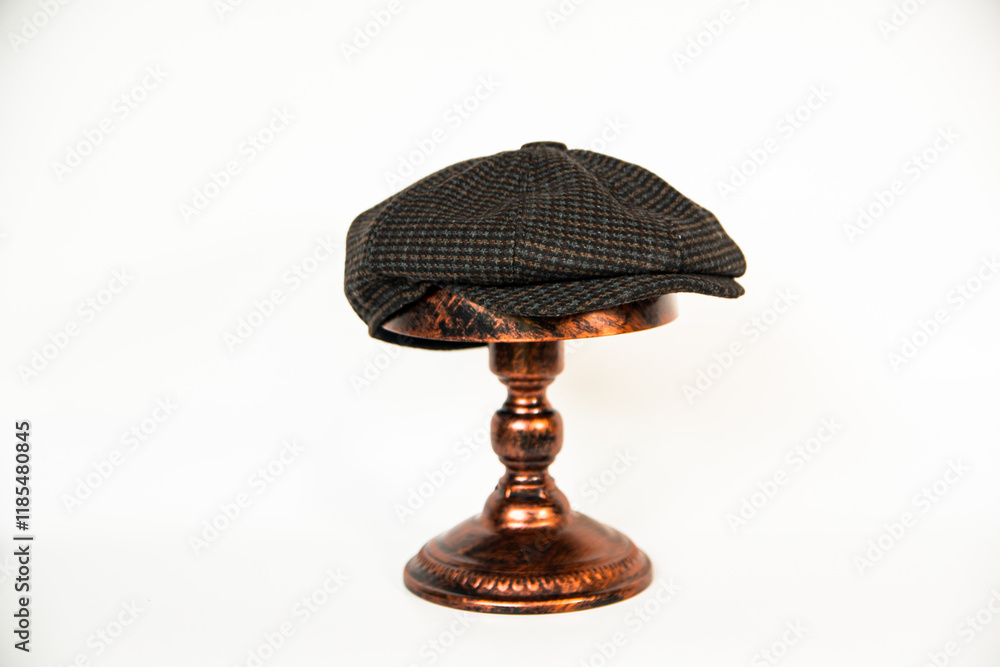 Detail of a newsboy hat made of wool fabric with a pattern mounted on a bronze mannequin head with a white background. classic newsboy hat photo concept on an elegant bronze mannequin Detail of a newsboy hat made of wool fabric with a pattern mounted on a bronze mannequin head with a white background. classic newsboy hat photo concept on an elegant bronze mannequin