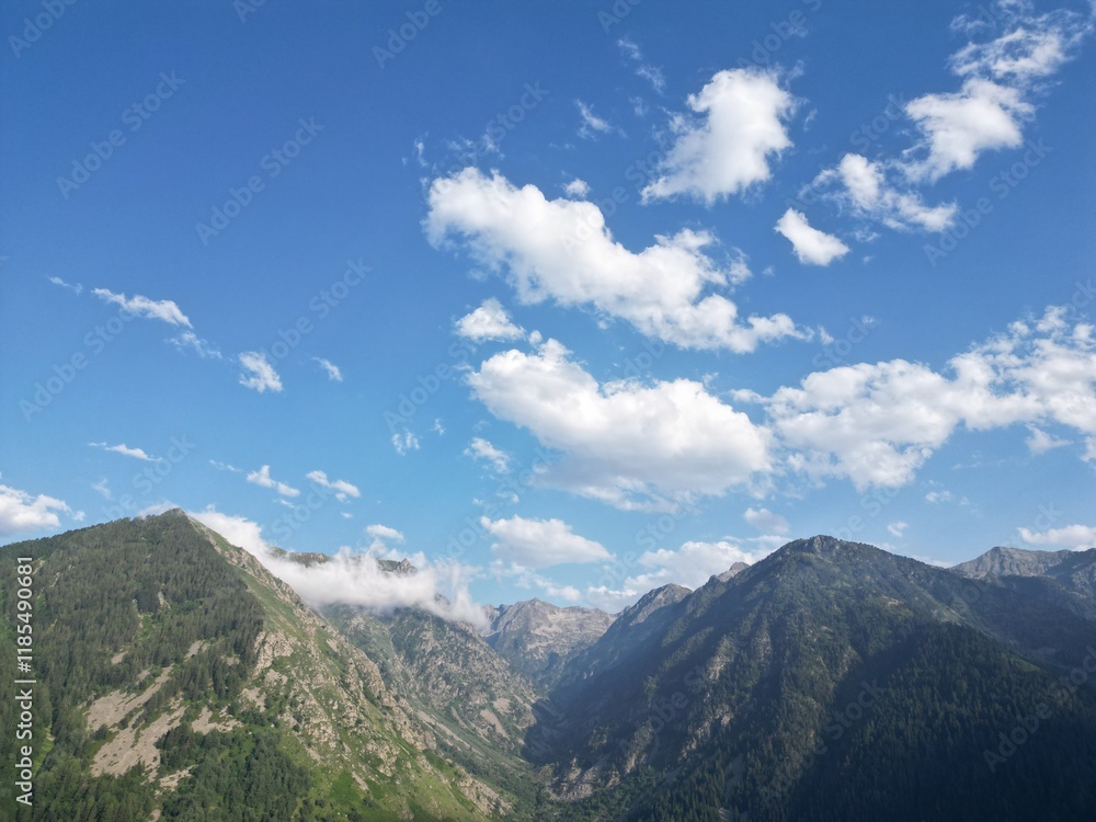 Aerial view of a mountain range with clouds under a blue sky - Vue aérienne d'une chaine de montagne avec des nuages sous un ciel bleu Aerial view of a mountain range with clouds under a blue sky - Vue aérienne d'une chaine de montagne avec des nuages sous un ciel bleu