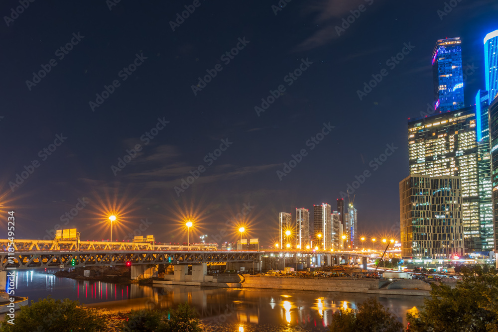 Fototapeta premium The scyscrapers of the Moscow City at night and the Dorogomilovsky bridge with illumination. Translation of text - street names: Krasnopresnenskaya, center, etc.