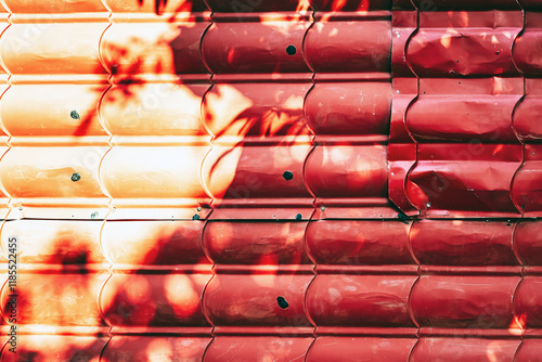 Artistic of old red metal tile fence background. Fence from corrugated board. Zinc metal sheet texture. Steel panel of enclosing wall. Old metallic sheet with peeling paint. Background or texture. photo