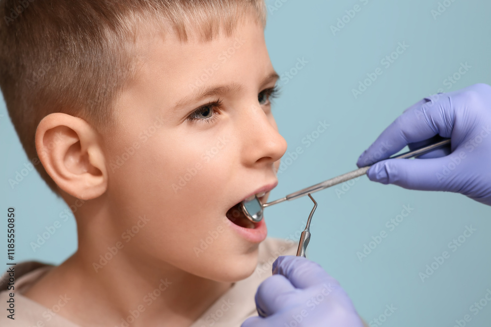 Obraz premium Dentist examining teeth of little boy on blue background