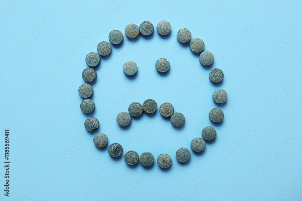 Sad face made of pills on blue background Sad face made of pills on blue background