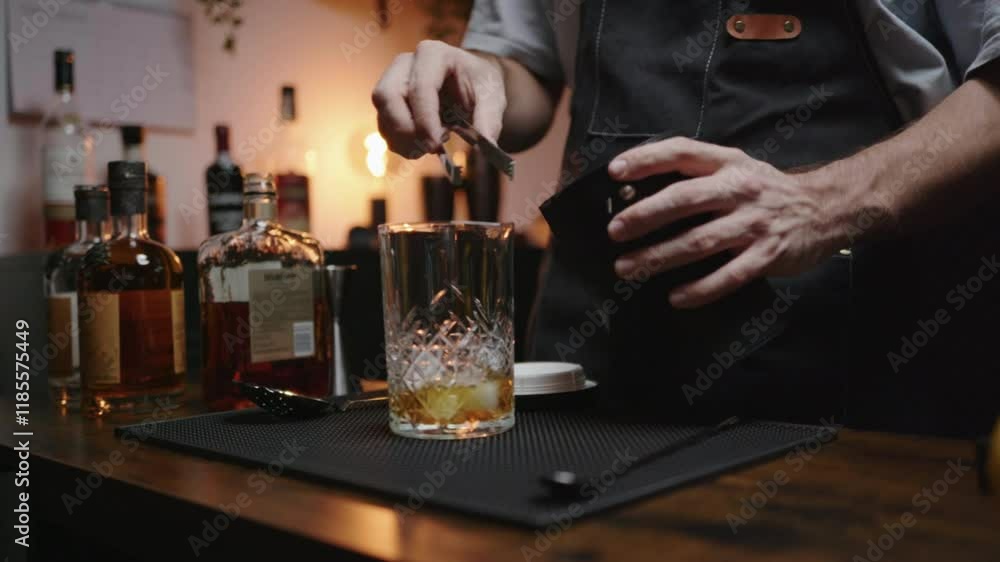 Bartender placing ice cubes into a high glass. Bartender crafting cocktail in cozy homebar. Perfect for beverage tutorials and mixology showcases. Bartender placing ice cubes into a high glass. Bartender crafting cocktail in cozy homebar. Perfect for beverage tutorials and mixology showcases.
