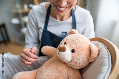 POV shot of happy smiling mother playing with teddy bear and baby in cradle photo