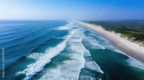 Aerial view of crashing waves on sunlit shore highlighting the contrast between ocean depth and coastline tranquility with ample space for text photo