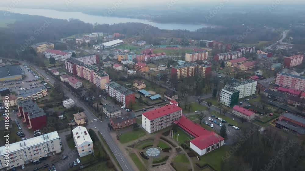Aerial photo of Balvi city bathed in warm sunset light, featuring urban buildings, parking lots, and a snow-dusted landscape. A peaceful winter scene. Aerial photo of Balvi city bathed in warm sunset light, featuring urban buildings, parking lots, and a snow-dusted landscape. A peaceful winter scene.