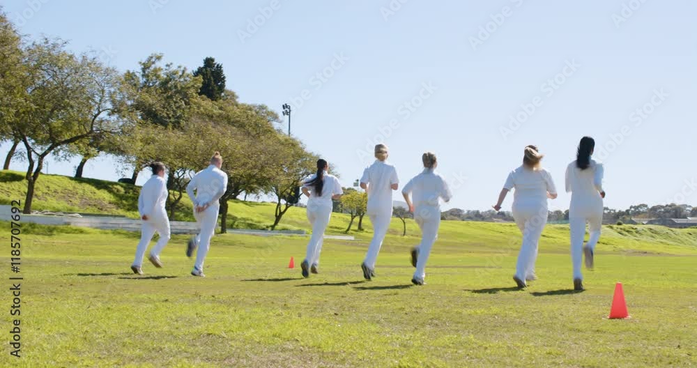 Playing cricket, women in white uniforms practicing on grassy field Playing cricket, women in white uniforms practicing on grassy field