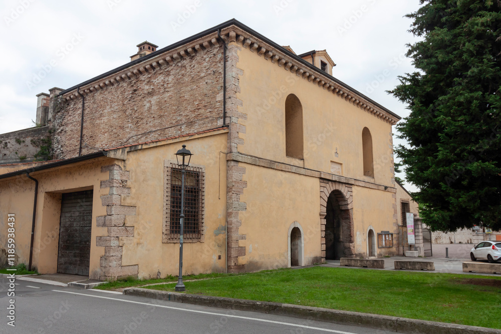 Obraz premium A view of a historic stone and brick building with arched openings, likely part of the fortifications or within the old town of Peschiera del Garda