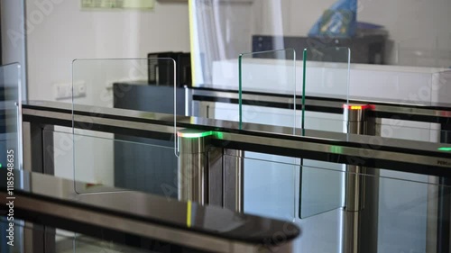 Passing through a turnstile into an office building. Office workers enter and exit through a modern turnstile, using a key card to enter.
