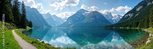 Serene alpine lake surrounded by towering mountains. Crystal clear water reflects vibrant blue sky. Green forest borders pathway. Peaceful atmosphere. Ideal for hiking, exploring. Scenic view of photo