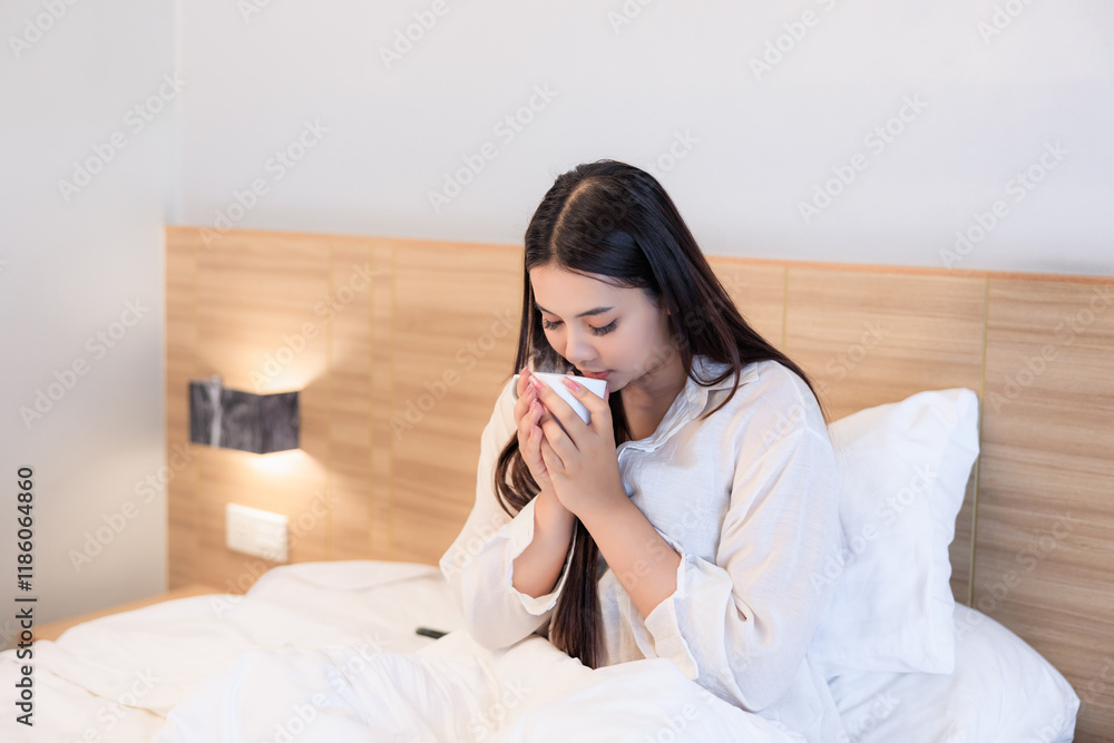 asian woman sitting on bed drinking coffee at morning time asian woman sitting on bed drinking coffee at morning time