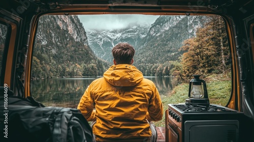 A person relaxes in the coziness of a camper, enjoying the tranquil view of a serene mountain lake, fitting for themes of adventure and travel photo