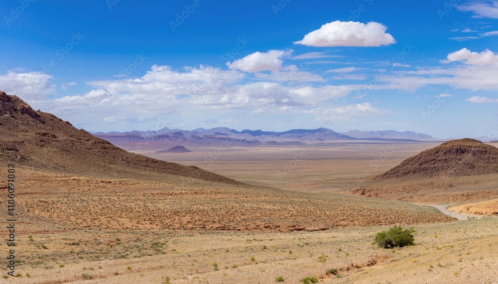 Fototapeta premium Vast desert landscape with mountains under a bright blue sky and scattered clouds. Nature and wilderness concept 