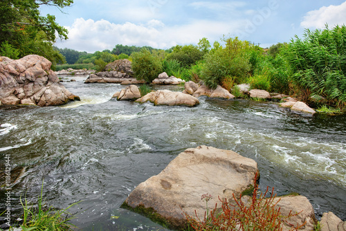 Serene river landscape with gentle rapids and lush greenery under a cloudy sky