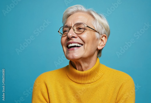 Portrait of a gray-haired mature woman in a yellow sweater on a blue background