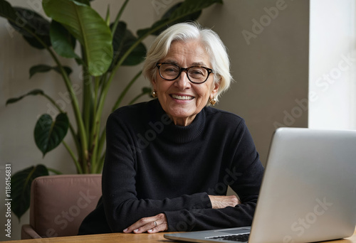 Portrait of gray-haired mature woman in black sweater working on laptop
