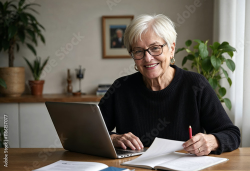 Portrait of gray-haired mature woman in black sweater working on laptop