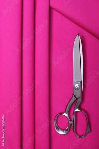 Top down view of fashion designers table with pink silky brocade on it and professional sewing scissors on top. One of the most popular solid color fashion fabrics after classical satins. photo